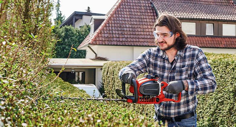 man working with einhell hedge trimmer